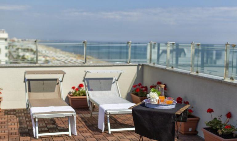 Terrazza con lettini, tavolino e vista mare.