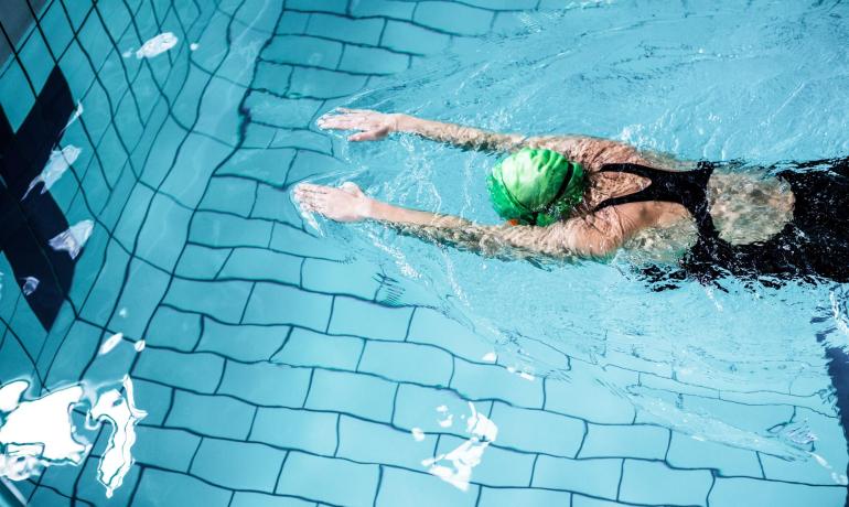 Nuotatore con cuffia verde in piscina.