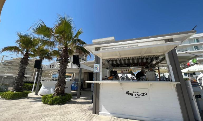 Chiosco sulla spiaggia con palme e cielo blu.