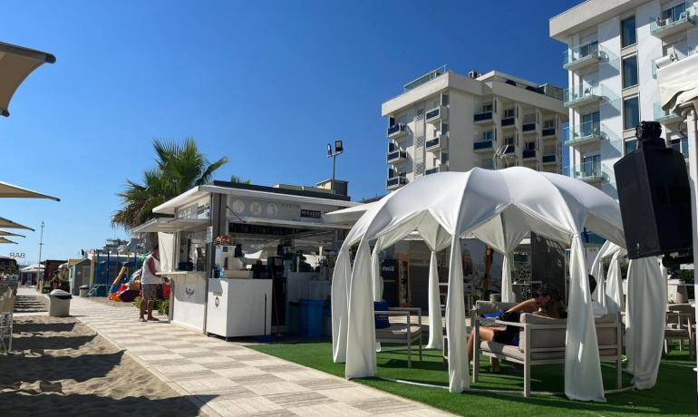 Spiaggia con bar e gazebo bianco, cielo limpido.