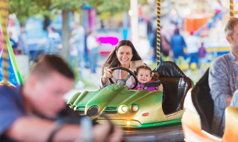 Donna e bambina su un'autoscontro in un parco divertimenti.